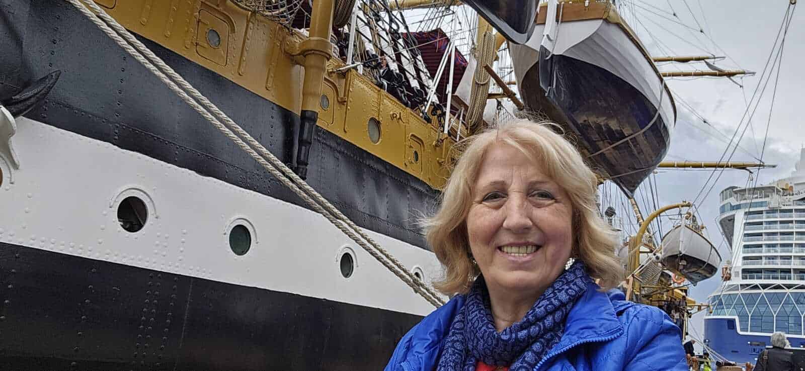 Amerigo Vespucci a Napoli 2025: cosa sapere 3 Nave da crociera storica e donna sorridente in primo piano, porto turistico con yacht e barche nel background, turismo marittimo, viaggio e avventure in mare.
