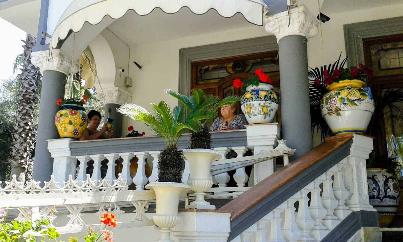 Fiorita veranda con piante e vasi di Ceramica dipinti a mano, decorata con colonne e ringhiere eleganti, ideale per relax e incontri estivi.