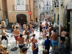 Bagno in strade affollate di persone che si rinfrescano in una calda giornata estiva in un centro storico italiano. Sfondo di edifici colorati e architettura tradizionale.
