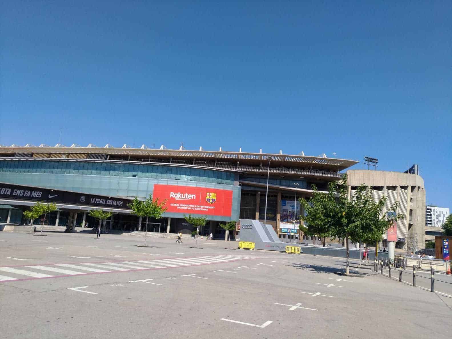 Stadio Olimpico Lluís Companys a Montjuïc, moderna ed imponente, con cielo sereno e parcheggio vuoto in prima piano.