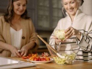 Sorelle che preparano insalata di verdure fresche in cucina, isotopo di convivialità e cucina italiana sana, alimentazione genuina e ricette tradizionali.