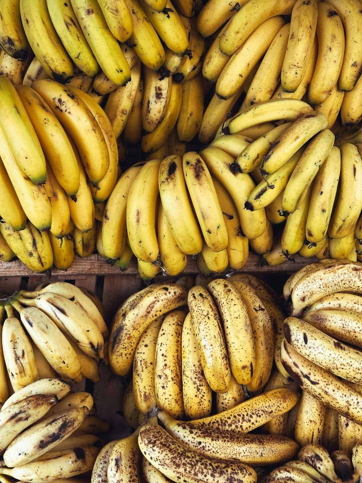 Banane fresche e mature vendute al banco del mercato, in diverse varietà e maturazioni, pronte per essere consumate o utilizzate in cucina.