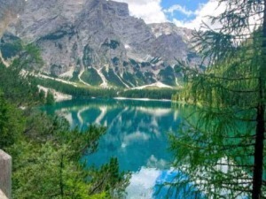 Vetta di una montagna riflessa in un lago alpino circondato da natura incontaminata e cielo nuvoloso, paesaggio mozzafiato, scenery montano, viaggio in natura, escursionismo.