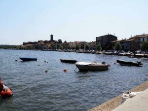 Barche nel porto di un villaggio pittoresco, con edifici storici e il mare calmo, perfetto per fotografare un paesaggio marittimo italiano.