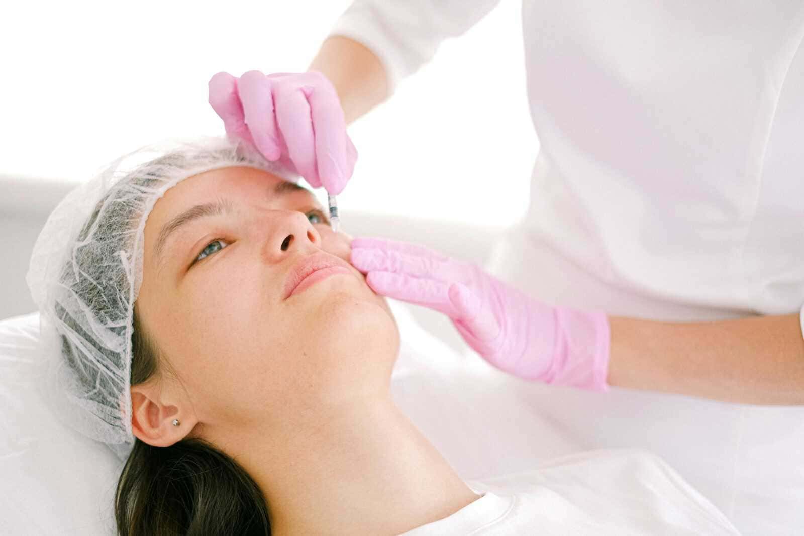 Esame del viso durante trattamento estetico, approccio professionale alla cura della pelle. Procedura di iniezione o trattamento di medicina estetica su una paziente femminile.