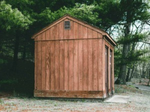 Cassetta in legno rustica in un'area naturale circondata da alberi verdi, perfetta per il camping o come rifugio nel bosco.