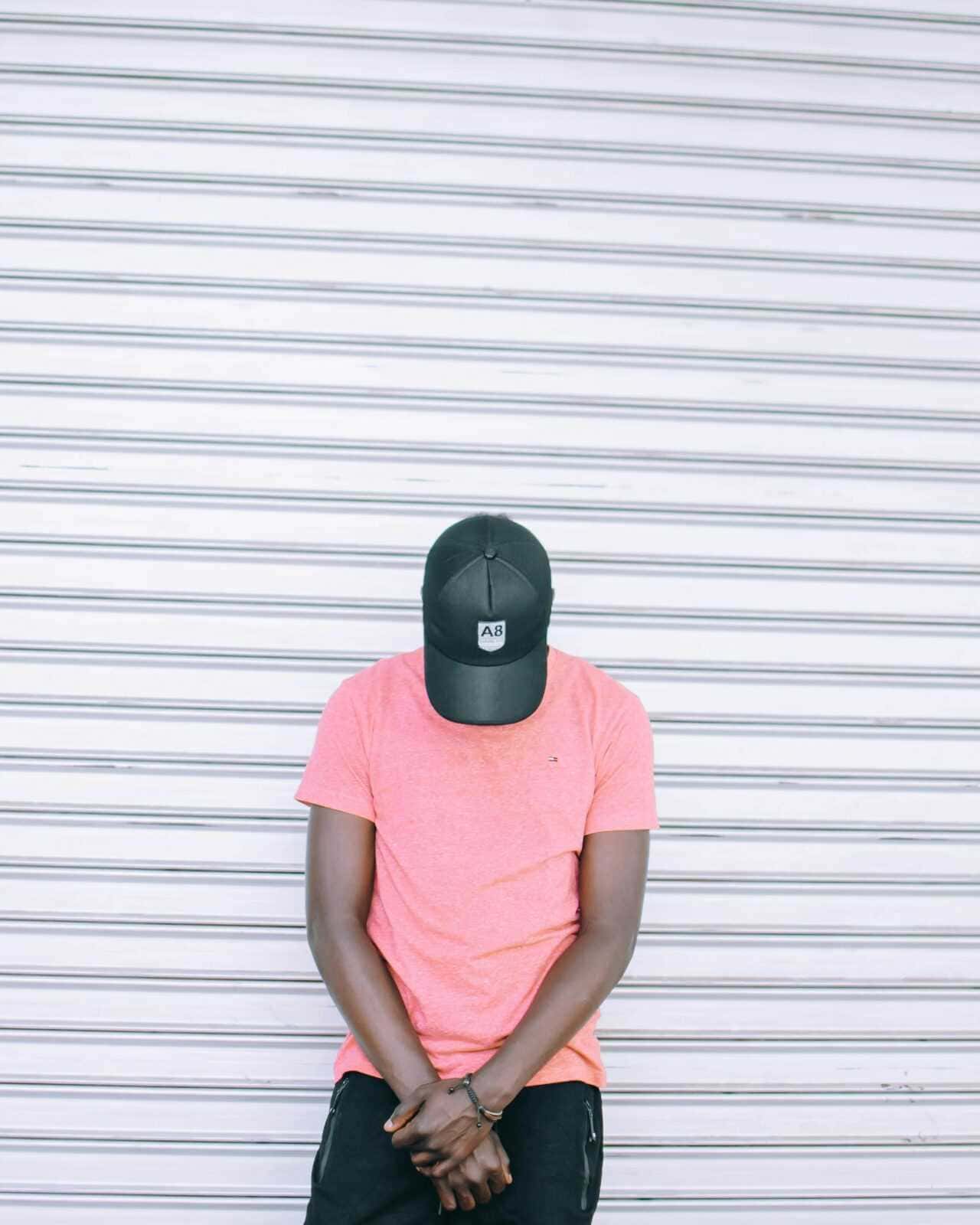 Capi di Abbigliamento Sportivo Indispensabili: A8 cappellino, persone giovani con abbigliamento casual, street style, sfondo di serranda metallica, moda urbana, stile casual, outfit estivo, look alla moda, tendenze streetwear, accessori moda, rap, hip hop, cultura di strada, self-expression, giovani artisti, fashion statement.