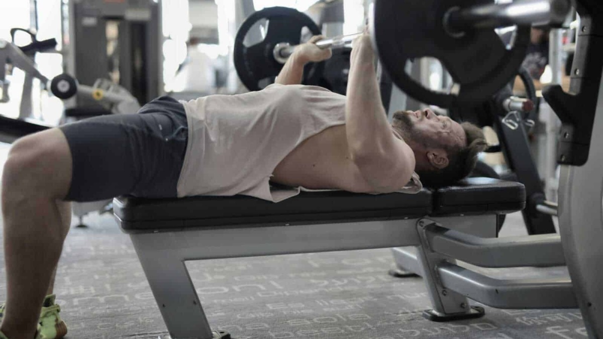 Sollevamento pesi uomo in palestra, allenamento muscolare, esercizio di sollevamento pesi, fitness e body building.