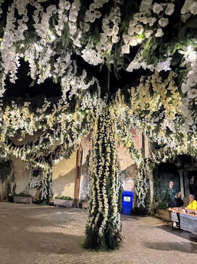 Un albero decorato con fiori bianchi e luci LED in un evento all'aperto, creando un'atmosfera magica e romantica. Perfetto come decorazione floreale per matrimoni e occasioni speciali.