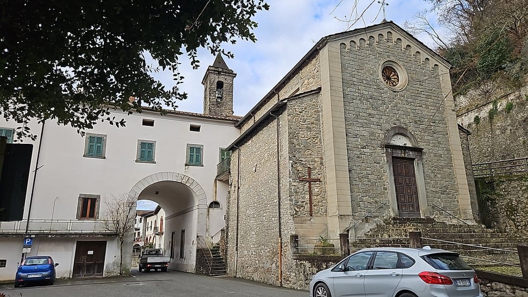 Bagnone cosa visitare nel centro storico: Castello malaspina: Vecchia chiesa in pietra a Montecchio, Italia, con ingresso principale e dettagli architettonici storici, circondata da veicoli e suggestivo paesaggio urbano.