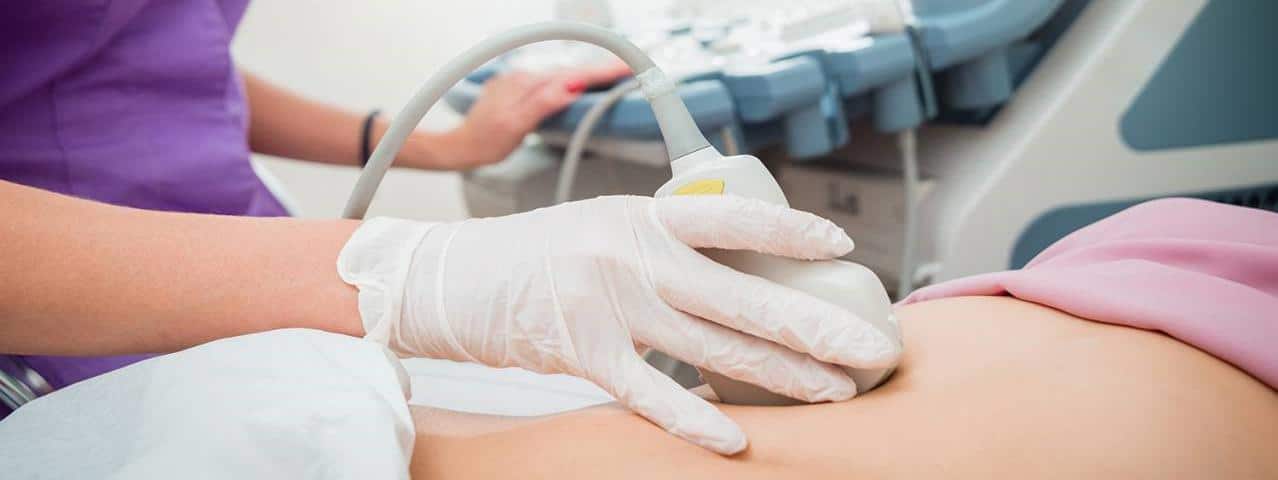 Ecografia in corso sulla pancia di una paziente, con medico che utilizza sonda per diagnosi medica, in ambiente clinico.