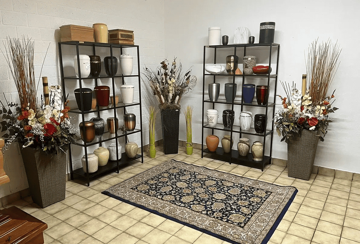 Vasi decorativi in ceramica e vasi in metallo su scaffali neri, disponibili in vari colori e materiali, con composizioni floreali e arredo di interni eleganti.