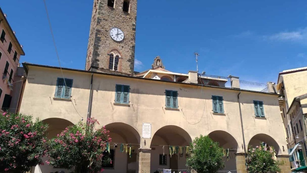 Splendida piazza storica nel centro di Town con le sue arcate e il campanile medievale, ambiente vivace con negozi, botteghe e passeggiata tra passeggini e persone.