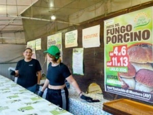 Festa del fungo porcino: stand con menu e informazioni sulla celebrazione del fungo porcino, con due donne dietro il banco in un evento culinario dedicato ai funghi.