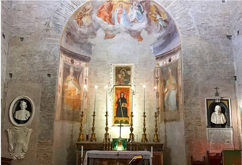 Alt text: Interno di una chiesa storica con altar, dipinti religiosi e statue, illuminata da candele e luci soffuse, che crea un'atmosfera di fede e spiritualità.