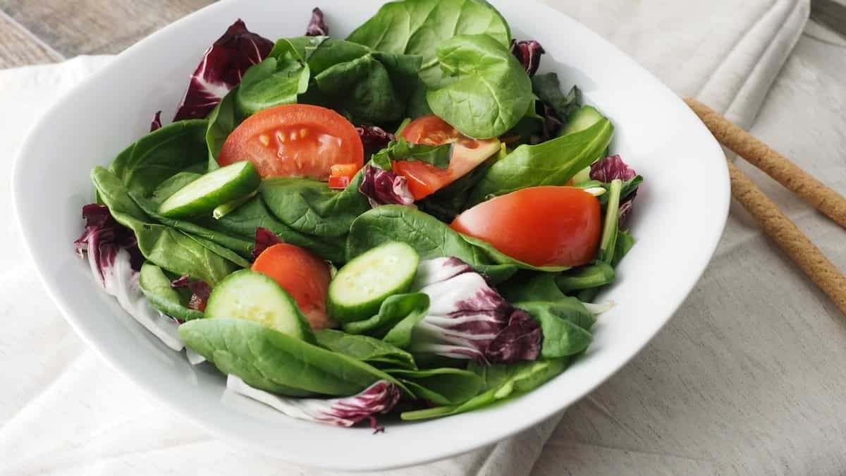 Pomodoro e lattuga fresca in insalata, alimentazione sana, ricetta vegetariana, alimenti biologici, cucinare a casa, cucina mediterranea.
