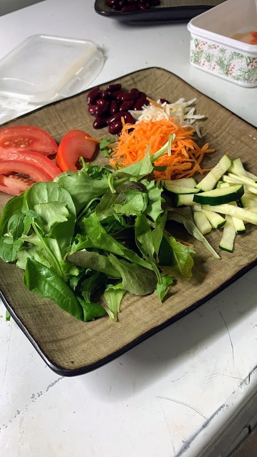 Nutrizione e salute: perché la prevenzione parte dall’alimentazione. Pomodori, insalata, carote, cetrioli e fagioli rossi freschi su tagliere di legno, preparati per un piatto di verdure salutari e naturali.