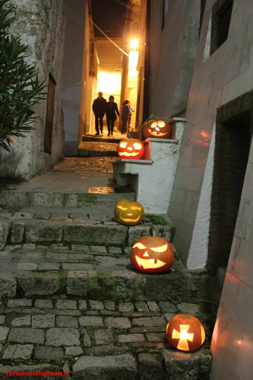Orsara Festa della zucca, la festa della luce 4 Carnevale, zucche di Halloween illuminate lungo i gradini di una vecchia strada in pietra. Atmosfera festa e mistero con luci calde e decorazioni spaventose, perfette per feste di Halloween in ambienti storici italiani.