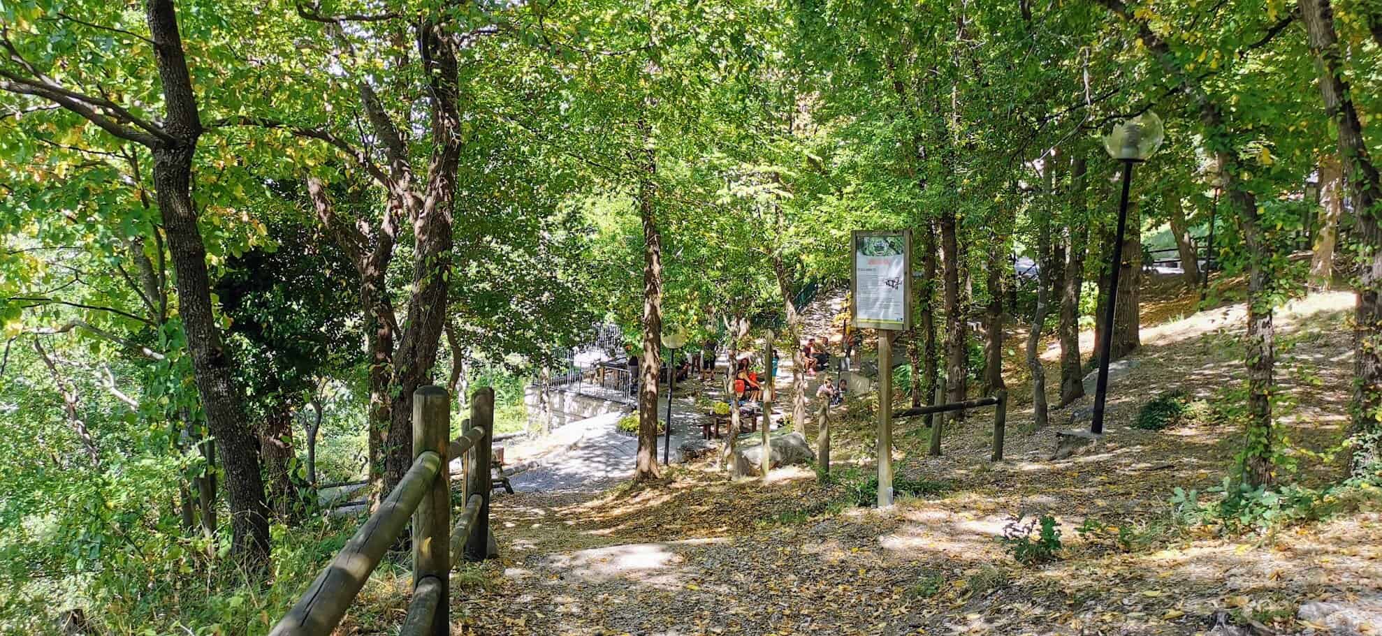 Via degli Dei in autunno: Fogliame autunnale e sentiero nel parco con panchine e illuminazione pubblica, ambiente naturale e rilassante, ideale per passeggiate e relax all'aperto.