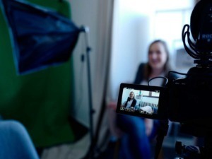 Comunicazione visiva: Videocamera professionale durante registrazione di un'intervista o vlog in studio, focusing on content creation, YouTube, e produzione video.