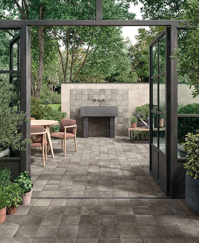 Finestra in vetro aperta, moderna terrazza giardino con posa di pavimento in pietra e area ristorante esterno.