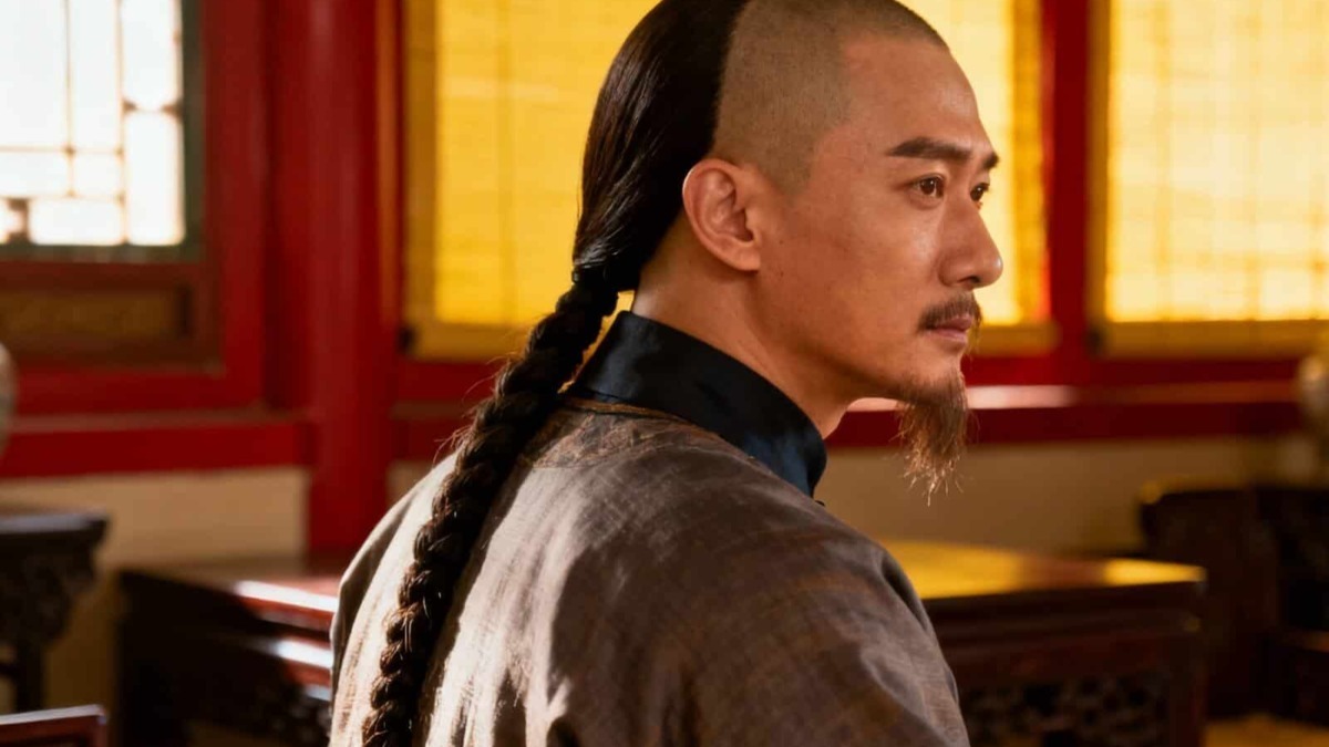 Sorgente di un personaggio con acconciatura tradizionale, in un ambiente storico di legno e feltro, caratteristiche per un contesto culturale orientale o cinematografico.