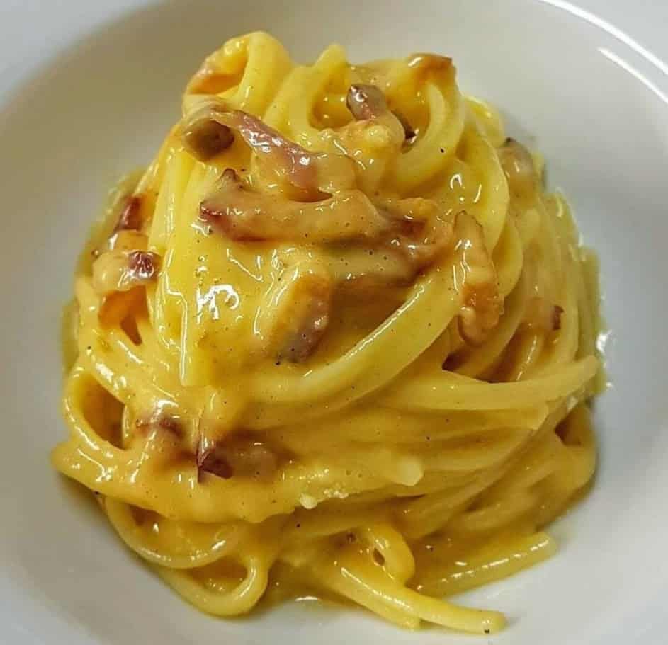 Deliziosi spaghetti alla carbonara preparati con pancetta croccante, uova e formaggio, perfetti per una cena italiana autentica e ricca di sapore.