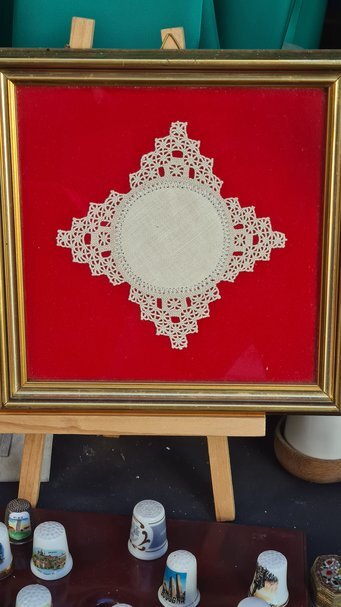 Ricamo tradizionale in pizzo su sfondo rosso.