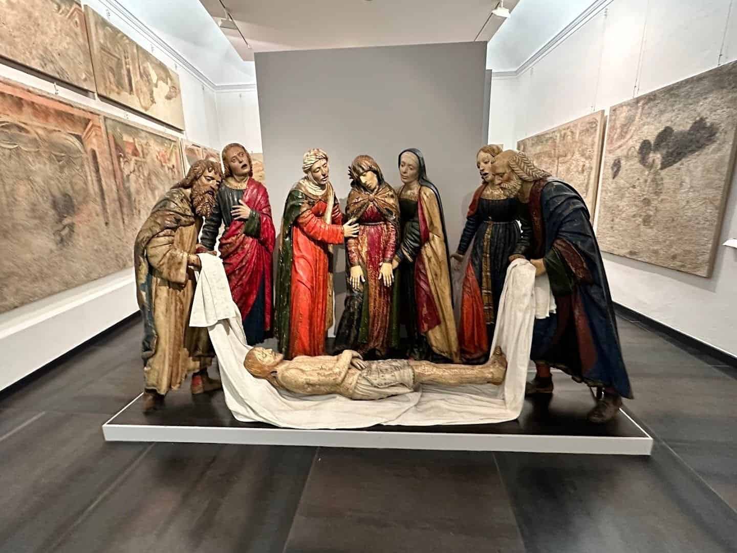 Vangeli e sculture sacre in mostra al museo, rappresentando scene religiose con dettagli artistici e storici.