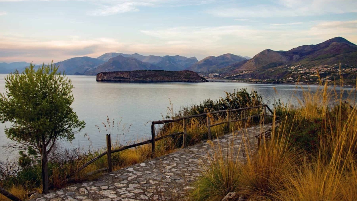 Paesaggio naturale con lago calabrese, montagne sullo sfondo e sentiero in pietra, perfetto per scoprire le bellezze del Sud Italia.