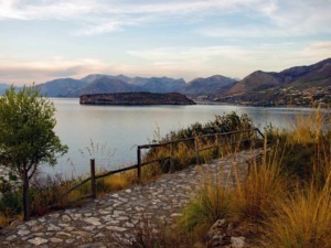 Paesaggio naturale con lago calabrese, montagne sullo sfondo e sentiero in pietra, perfetto per scoprire le bellezze del Sud Italia.