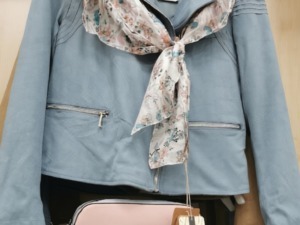Giacca blu con sciarpa floreale abbinata, perfetta per la stagione primaverile, in esposizione in un negozio di abbigliamento.
