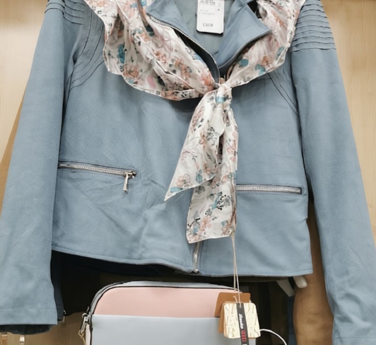Giacca blu con sciarpa floreale abbinata, perfetta per la stagione primaverile, in esposizione in un negozio di abbigliamento.