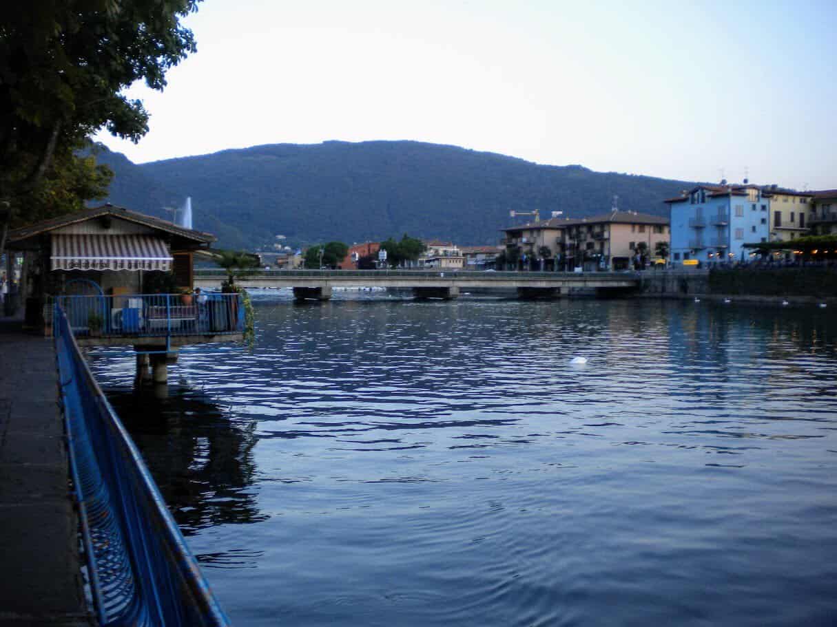 Ponte sul fiume Oglio a Sarnico con vista sulla città e montagne circostanti, ideale per scattare foto panoramiche e godersi il paesaggio naturale e urbano.