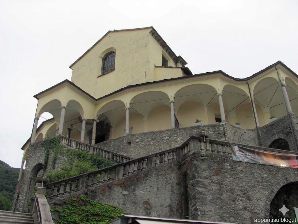 Casa storica su collina con portico e mura in pietra, vista dall'alto.