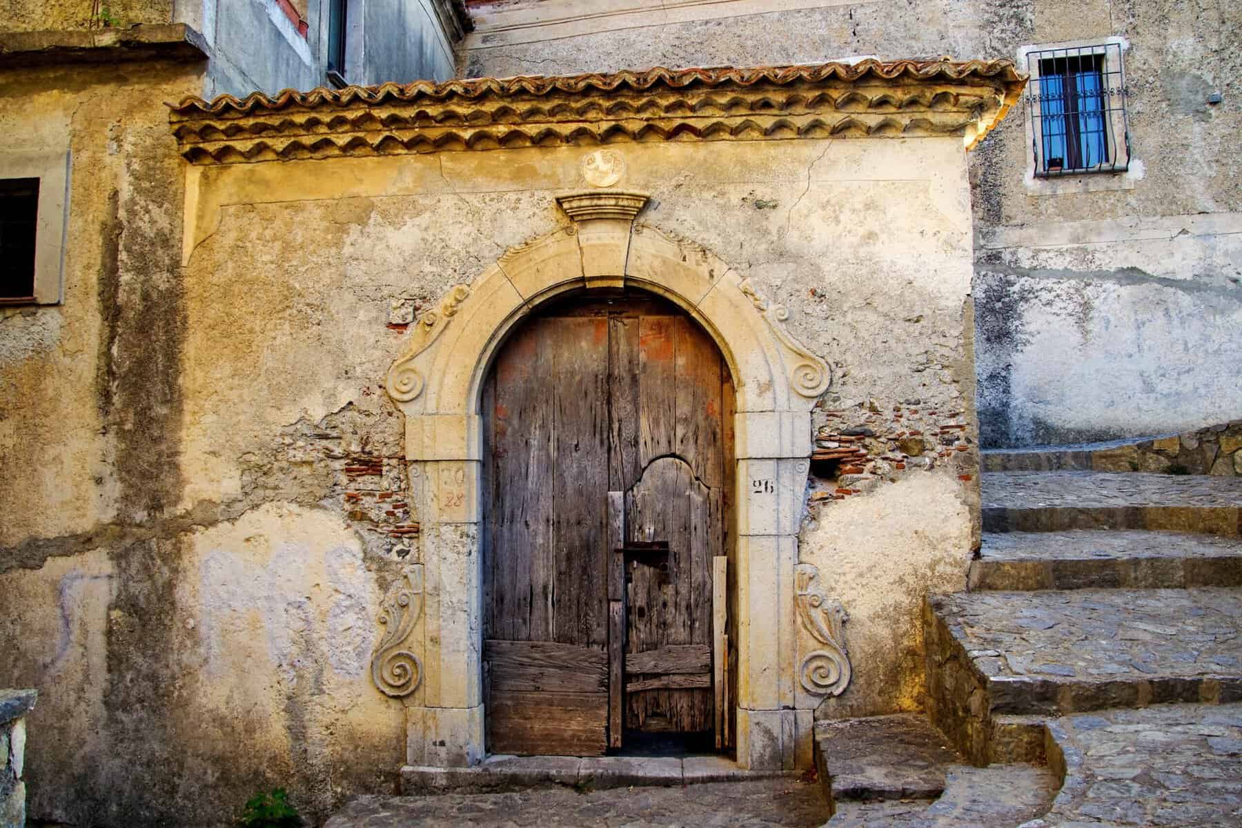 Portale in pietra e legno in un edificio storico del Sud Italia.