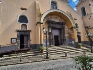 Facciata della chiesa di Sant'Egidio del Monte Albino con ingresso principale e dettagli architettonici, sotto un cielo azzurro con nuvole.