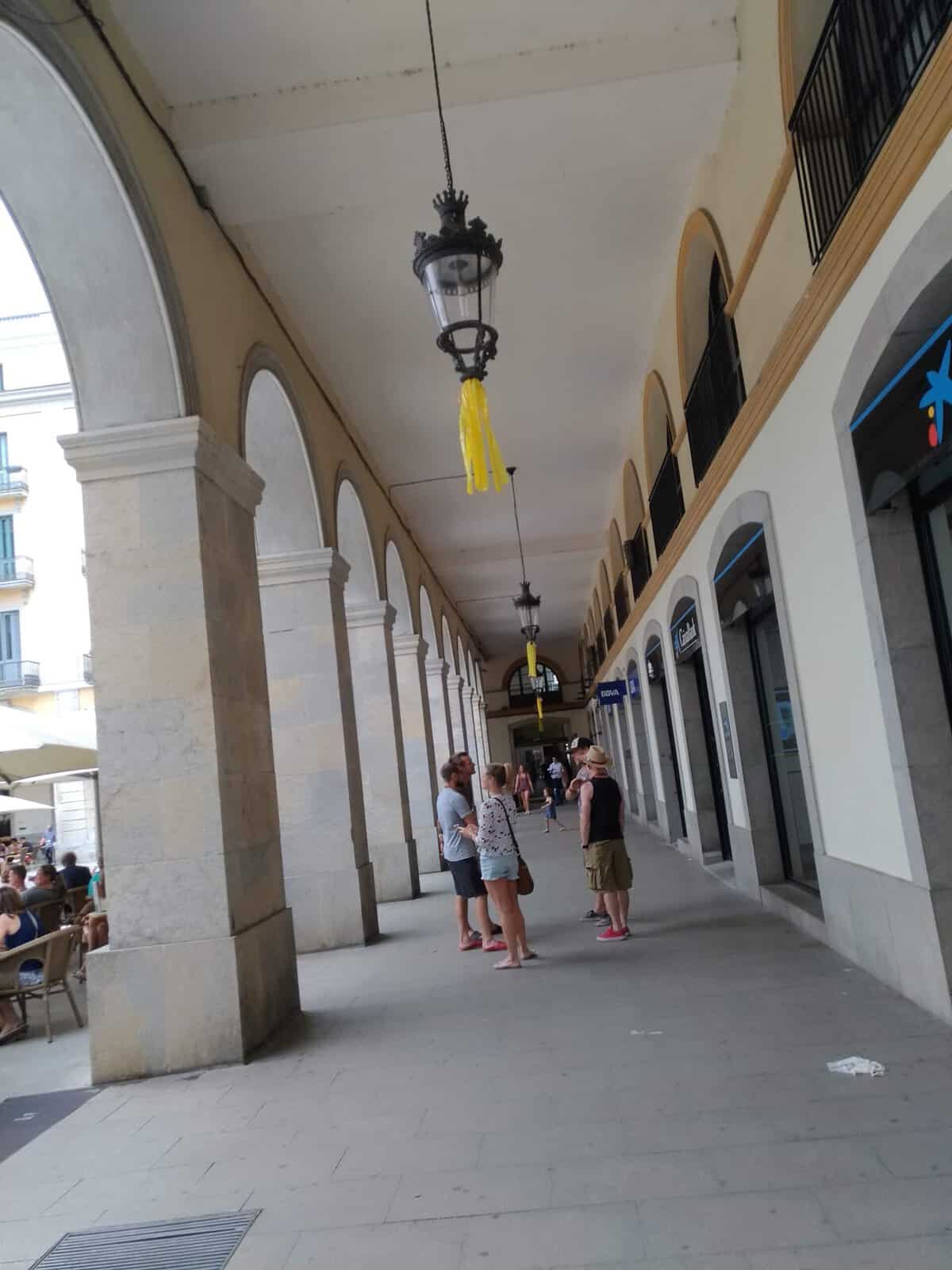 Cosa vedere a Girona in un giorno 6 Passeggiata sotto portici storici con persone che conversano e negozi sul lato destro.