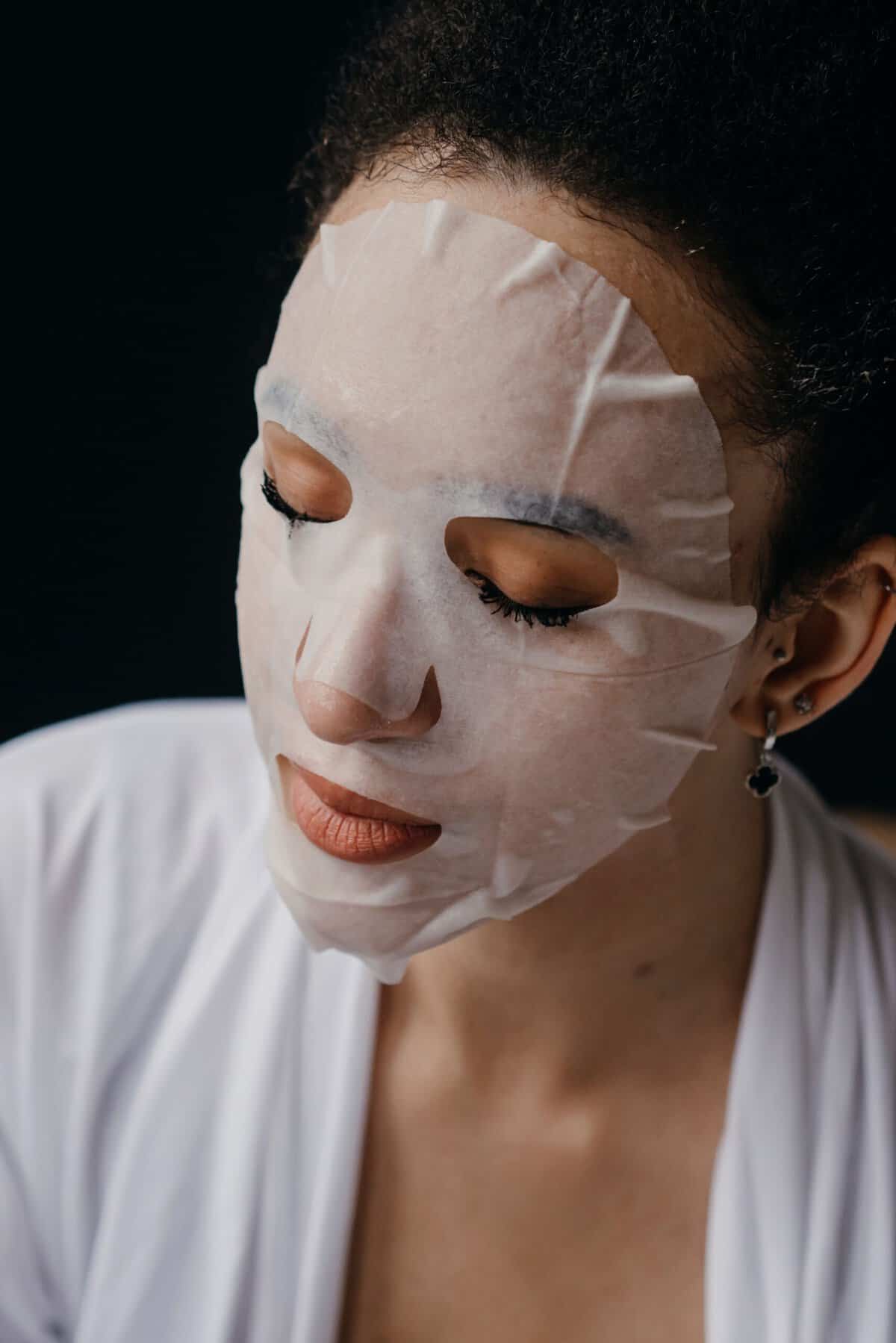 Maschera notte o maschera in tessuto: Close-up di una donna che usa una maschera idratante per la routine di cura della pelle, promuovendo la cura del viso a casa