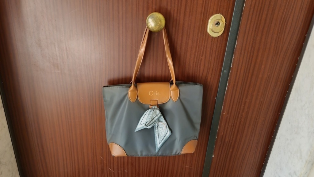 Borsa verde Callie appesa al pomello della porta di ingresso